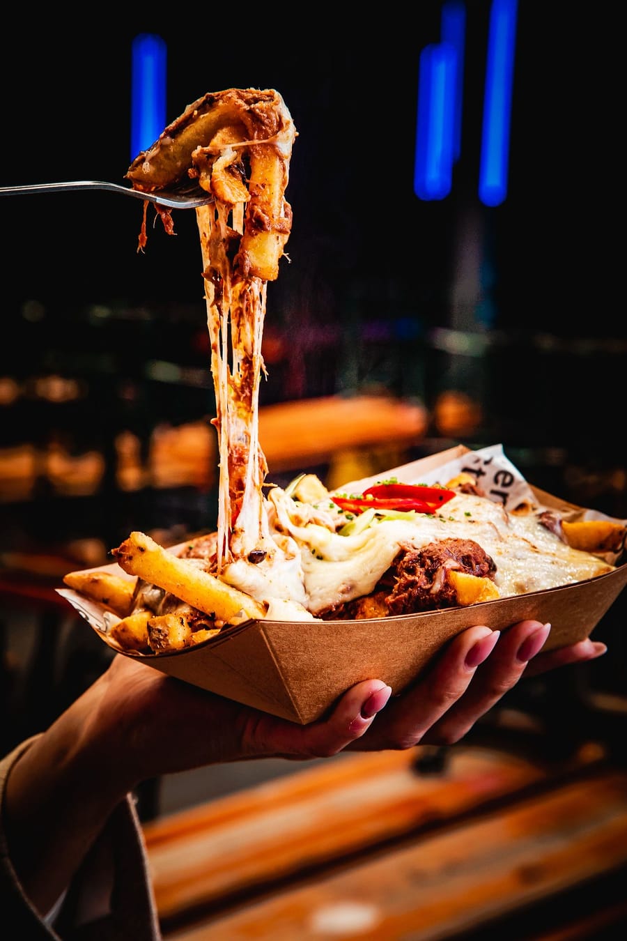 A fork lifting a long cheese pull from a loaded tray at Ten Streets Social