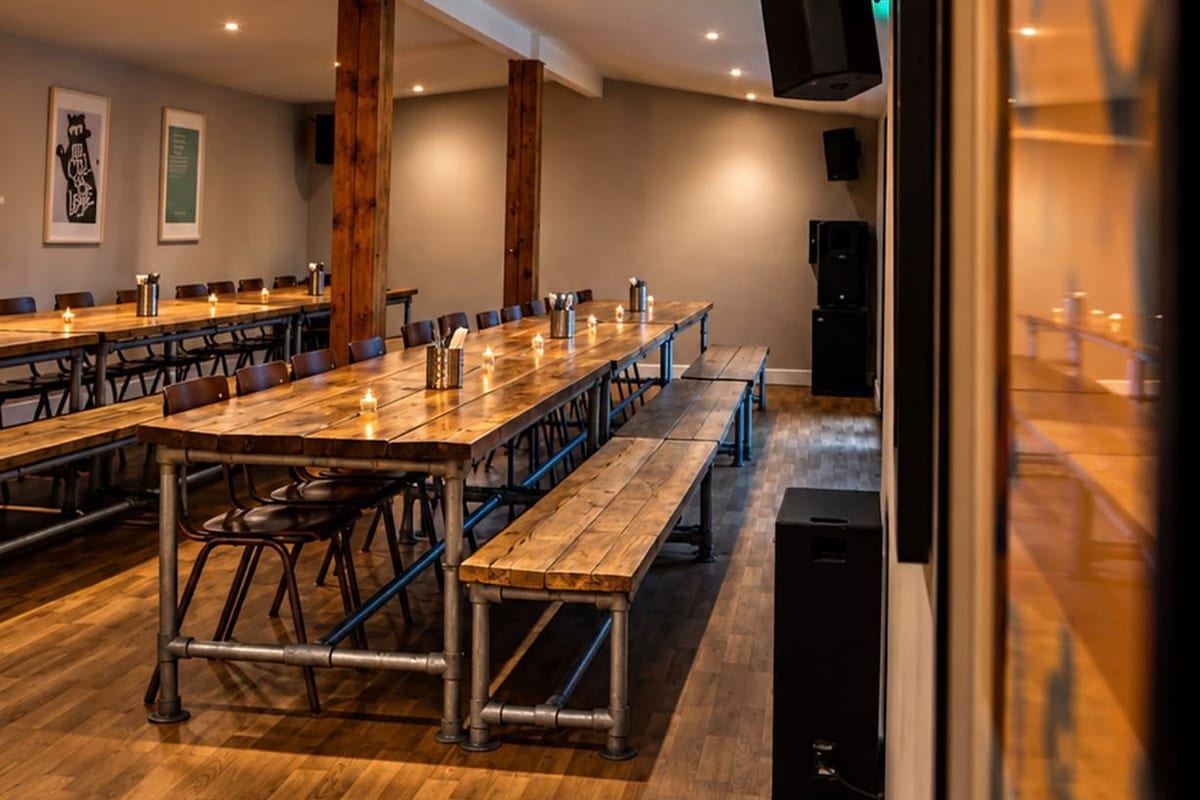 Long timber tables set with candles in the private dining room at Ten Streets Social