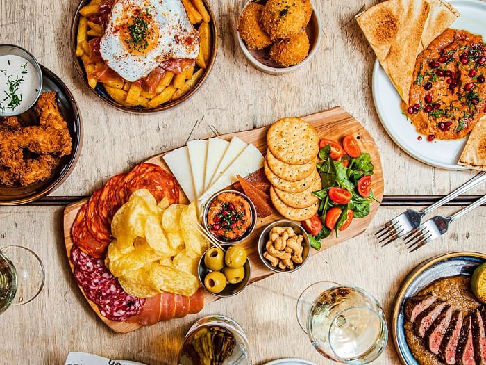 A full table of sharing dishes at Ten Streets Social - charcuterie and cheese, olives, flatbread, dips, bread and wine, from above