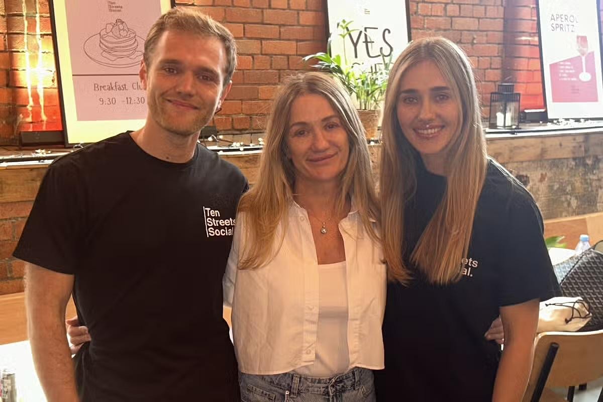 Three of the Ten Streets Social team smiling together in the dining room, in Ten Streets Social T-shirts