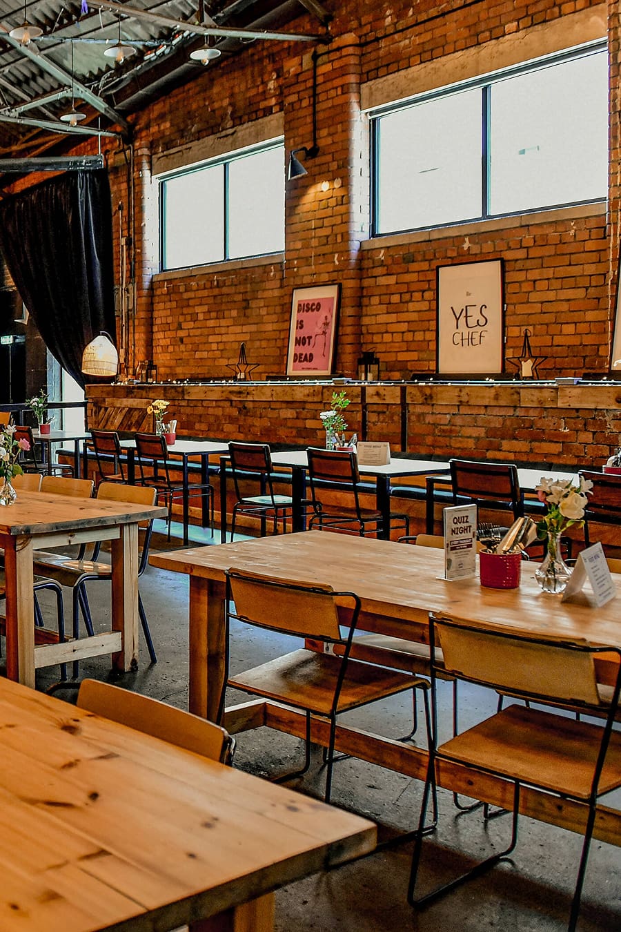 Timber tables and gallery posters inside the Ten Streets Social warehouse